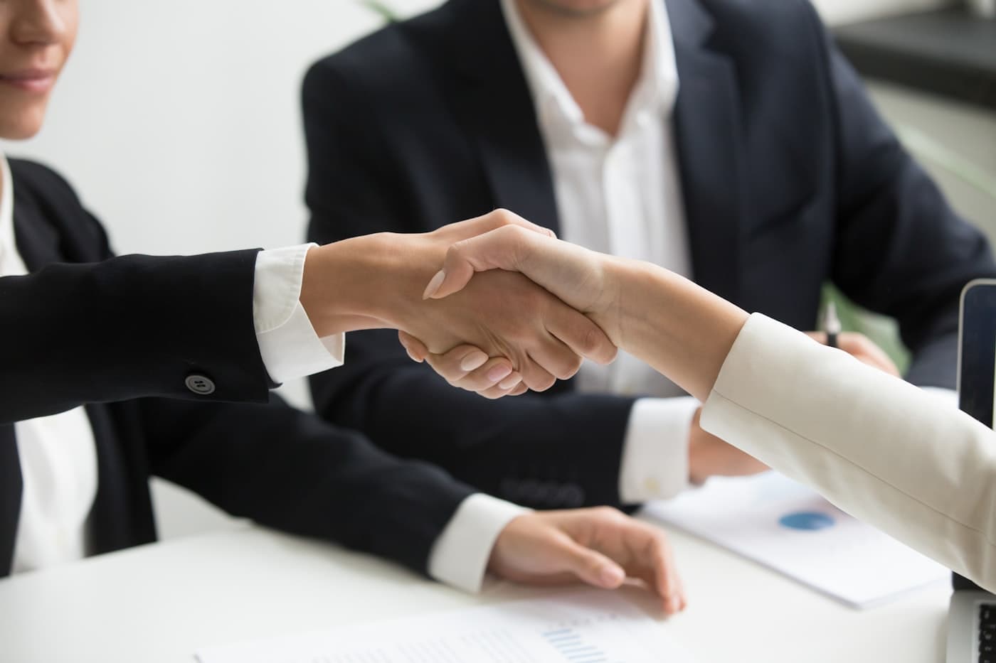 Dos personas cerrando un acuerdo comercial con un apretón de manos